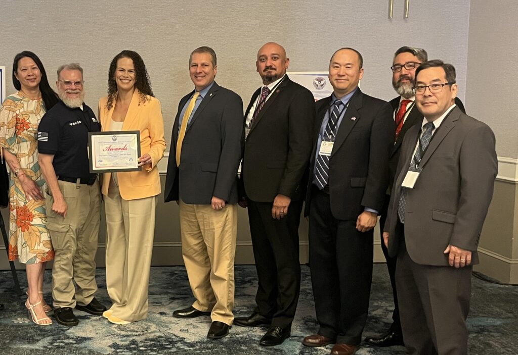 LADWP CEO Janisse Quiñones stands holding a certificate. She is flanked by another female employee along with six other male employees representing military veterans during acceptance of an award.