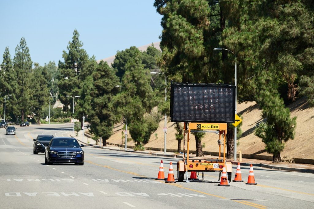 Car driving in street past sign on Boil Water Notice 