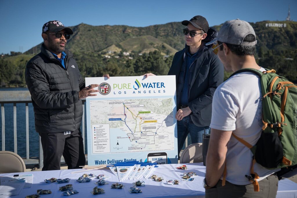 Members of the Pure Water Los Angeles team speak with an attendee about how water is delivered to Los Angeles using a regional water supply map during Reservoir Walk.