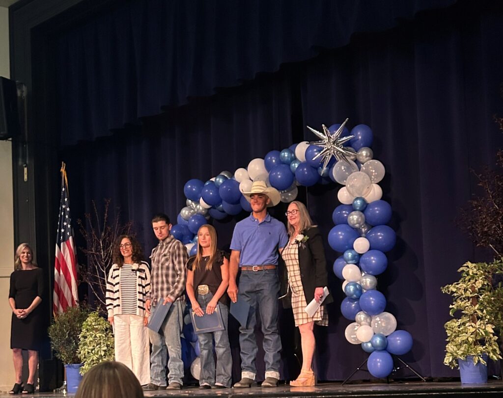 Awards are presented on stage with three students standing in the center and LADWP staff positioned on each side.